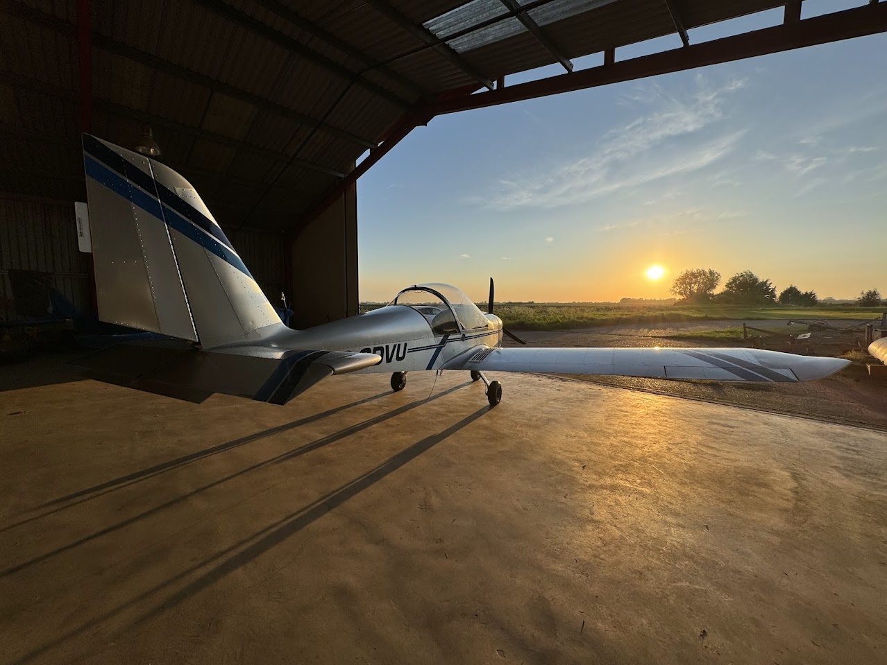 Aircraft beside the hangar at sunset